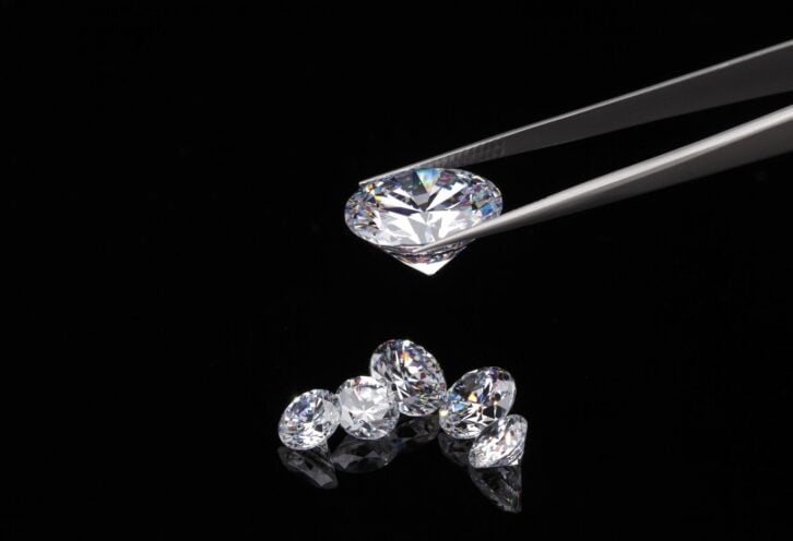 A round brilliant cut diamond held in tweezers