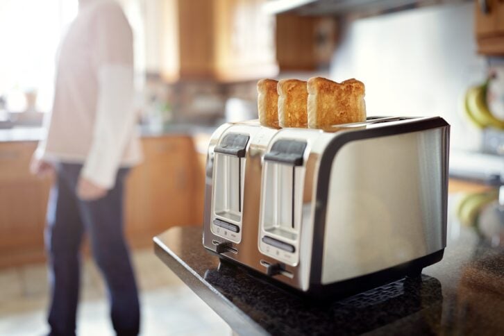 toaster on countertop of kitchen with person in background