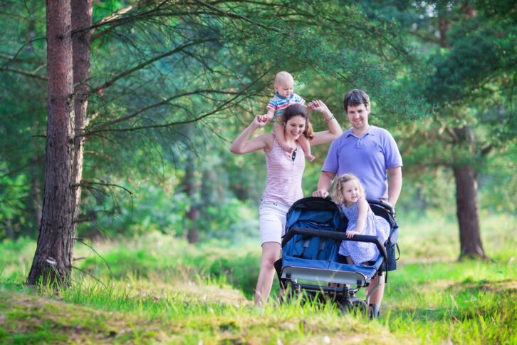 active parent hiking with two kids in a stroller