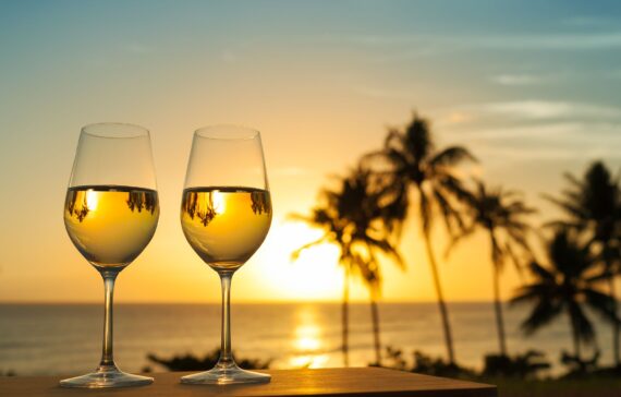 Romantic glass of wine setting by a Maui beach against a beautiful sunset