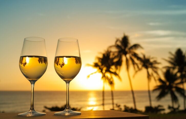Romantic glass of wine setting by a Maui beach against a beautiful sunset