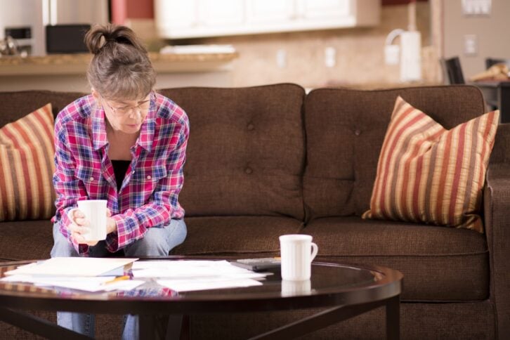 woman sitting on couch looking at bills