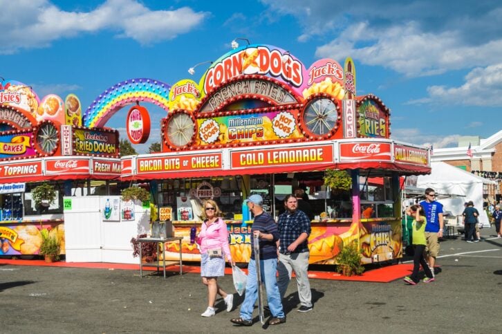 West Springfield, Massachusetts, USA - September 18, 2014: Fairgoers stroll past a colorful food concession at the Eastern States Exposition. With dozens of  food venues throughout the fairgrounds, bright displays are required to attract customers