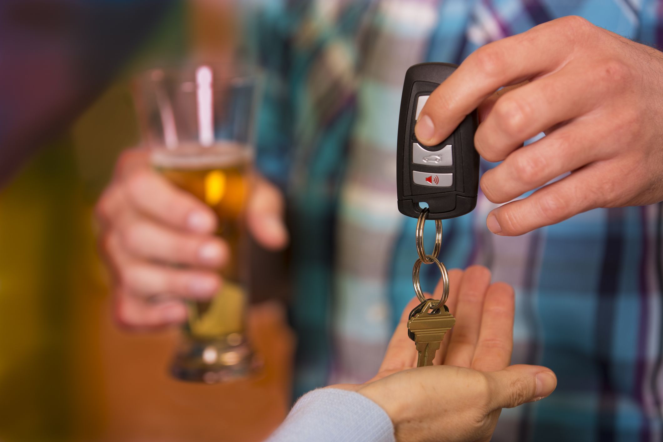 Man gives his car keys to a designated driver friend after he has been drinking too much at nightclub. Beer glass.