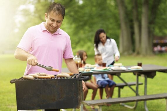 family grilling meat in park