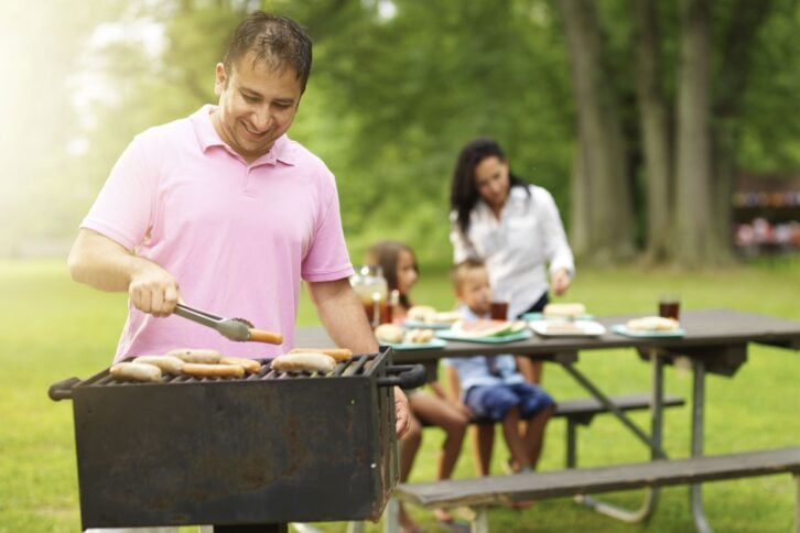 family grilling meat in park