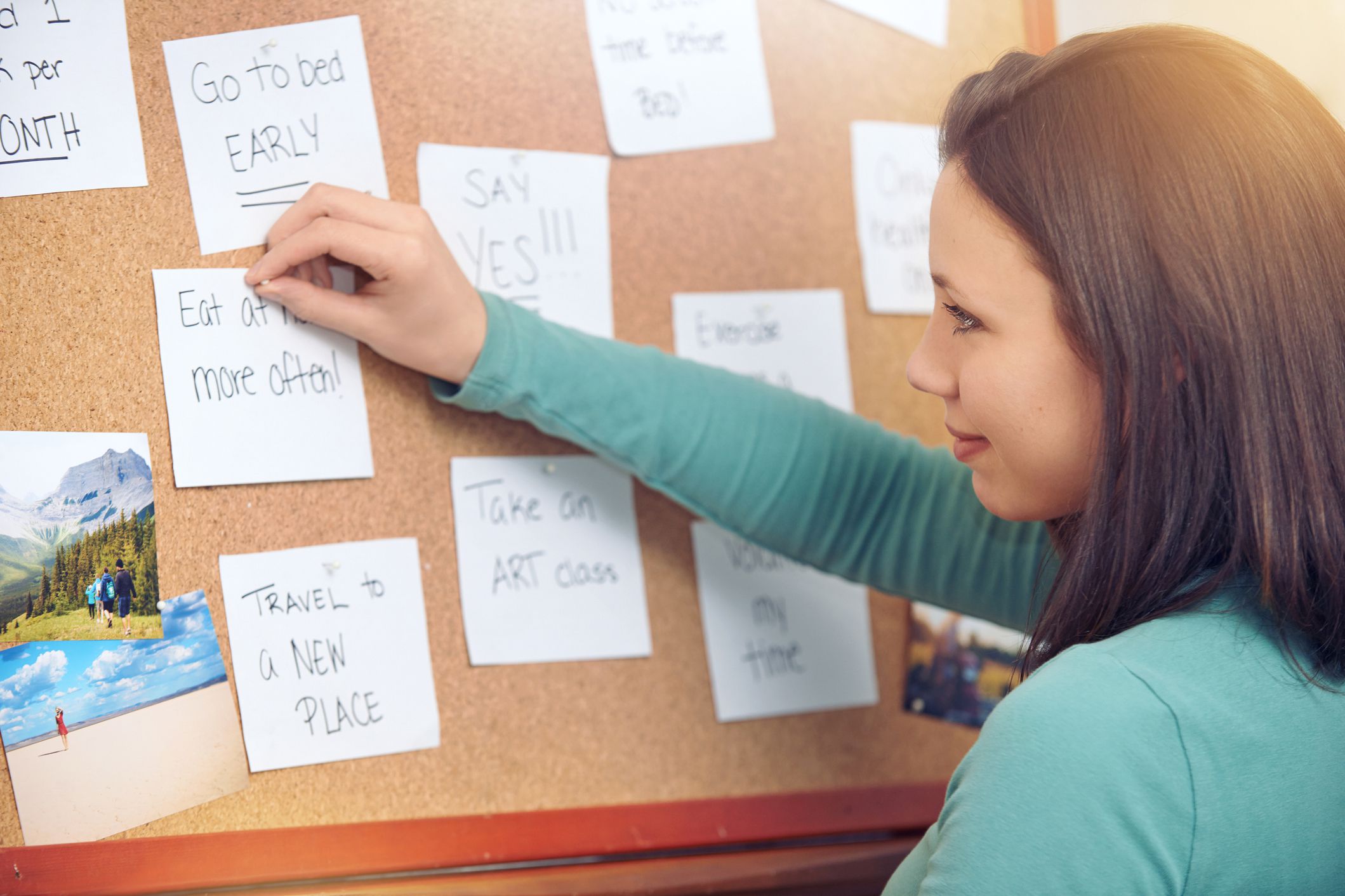 woman pinning goals to cork board