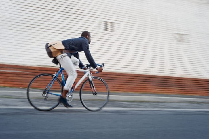 Black african mad riding bicycle in urban city commuting with speed and hipster trendy transportation