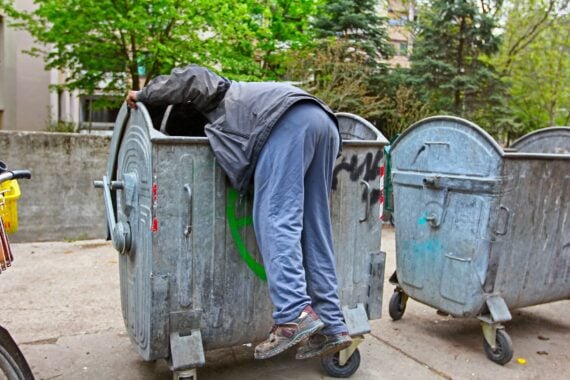 Homeless man is search for food in garbage