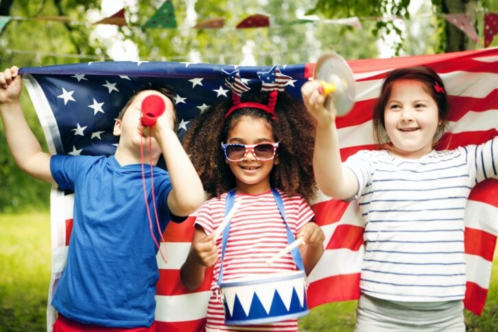 kids with 4th of july toys holding flag