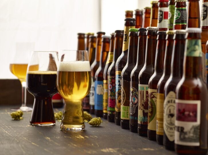 Still Life arranged in a photostudio. Beer tasting scene. Many different beer bottles from international breweries from Europe and USA. Dark and light beer served in typical glasses. This picture wants to show that tasting beer can be similar to tasting w
