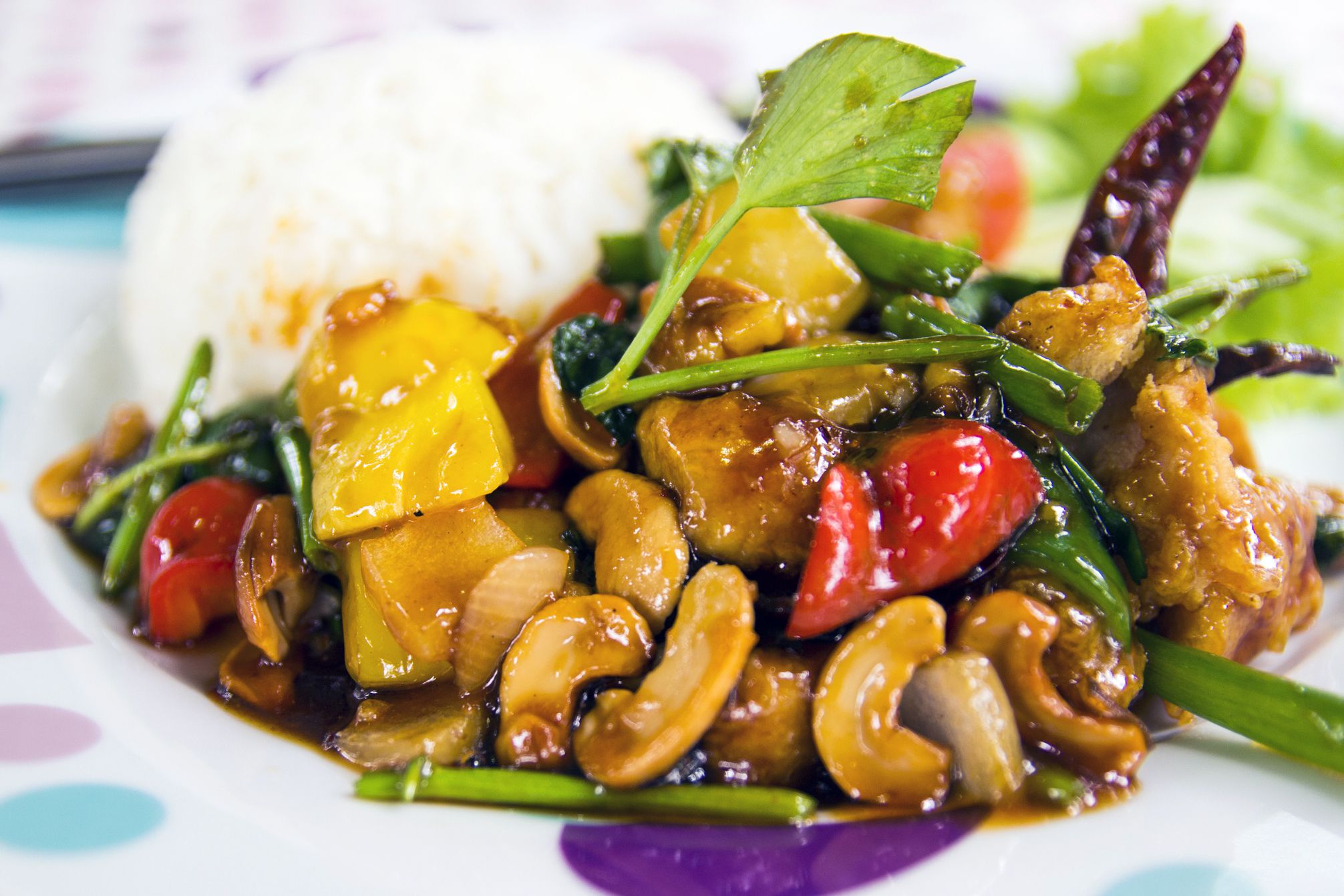 cashew stir fry with mixed peppers, chicken and rice on spotted plate