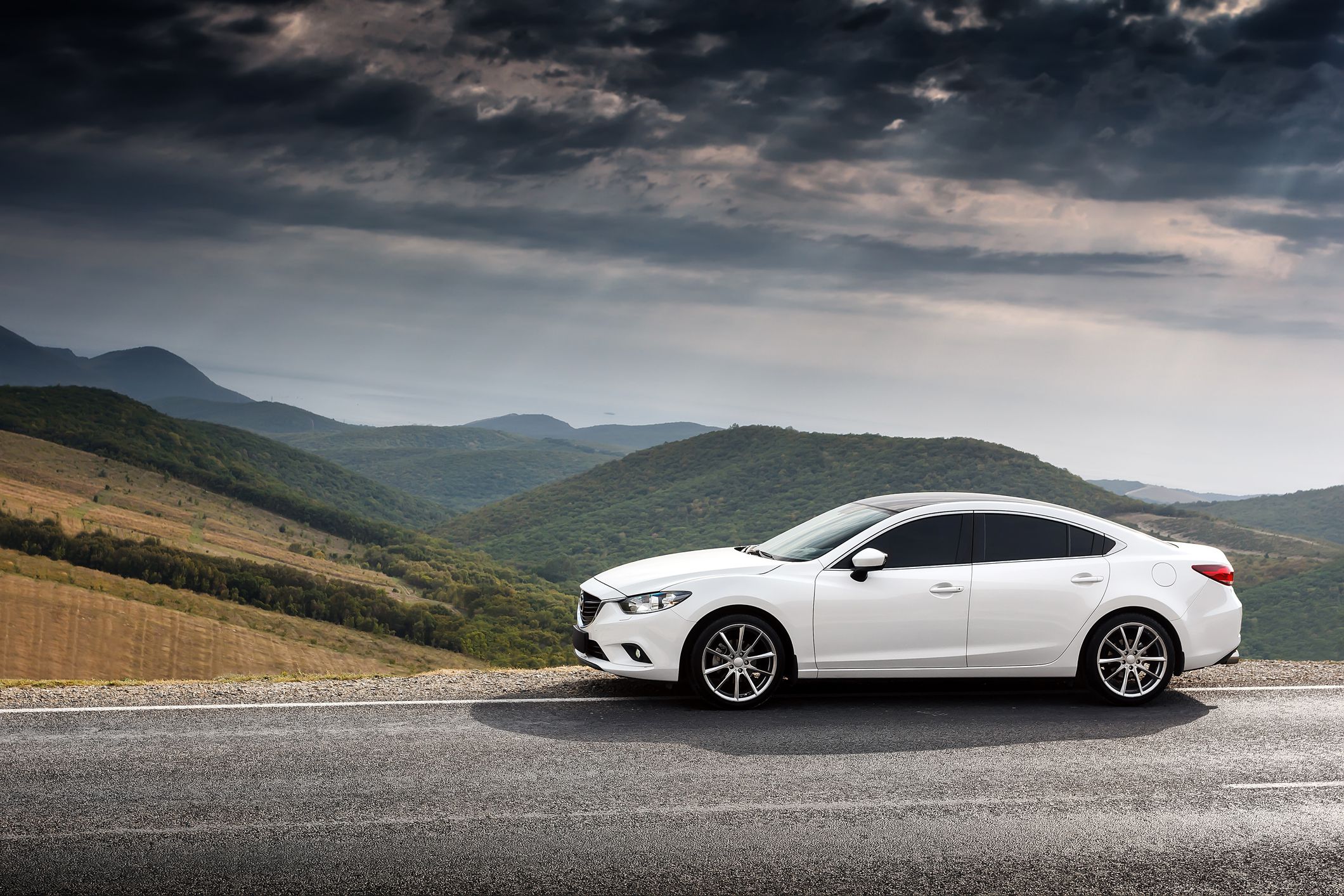 Krasnodar, Russia - September 07, 2014: White Car Mazda 6 parket at countryside asphalt road near green mountains at daytime