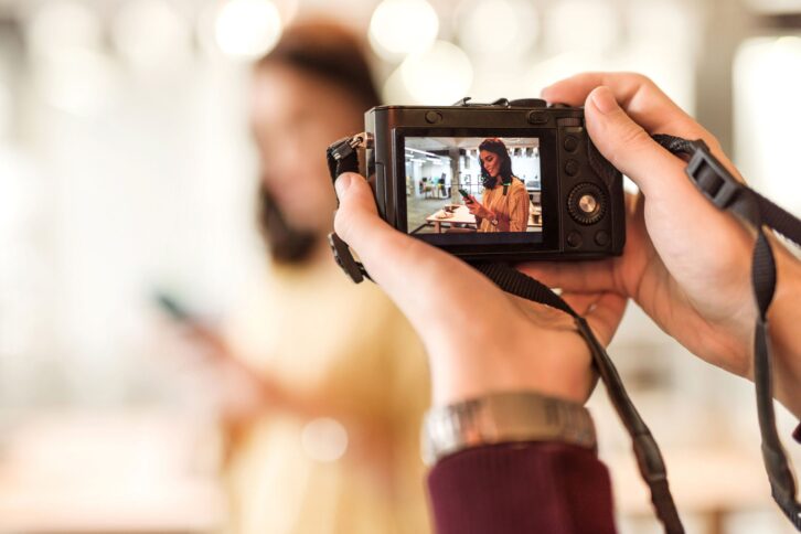 friend taking picture with digital camera of a female friend