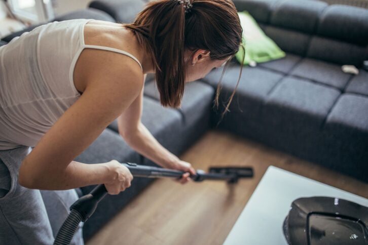 woman cleaning floor with vacuum cleaner