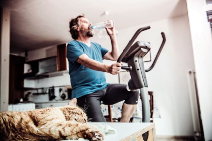 senior man exercising at home on exercise bike