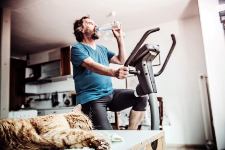 senior man exercising at home on exercise bike