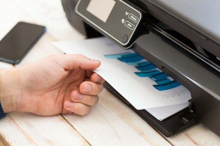 hand getting printed paper out of printer