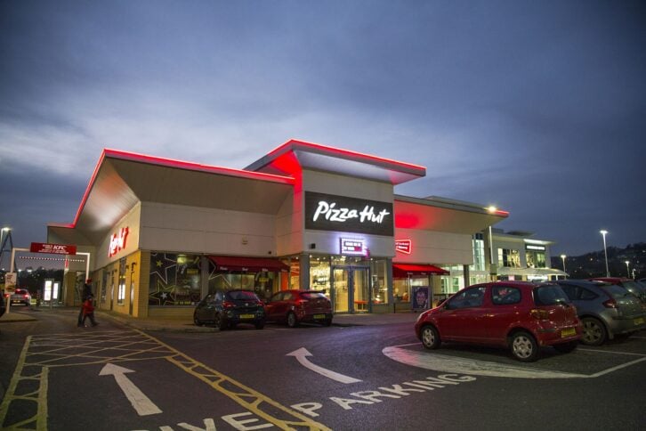 Swansea, UK: December 27, 2016: People walk past a night time drive through. Pizza Hut is an American restaurant chain and international franchise, known for its Italian-American cuisine menu including pizza and pasta.
