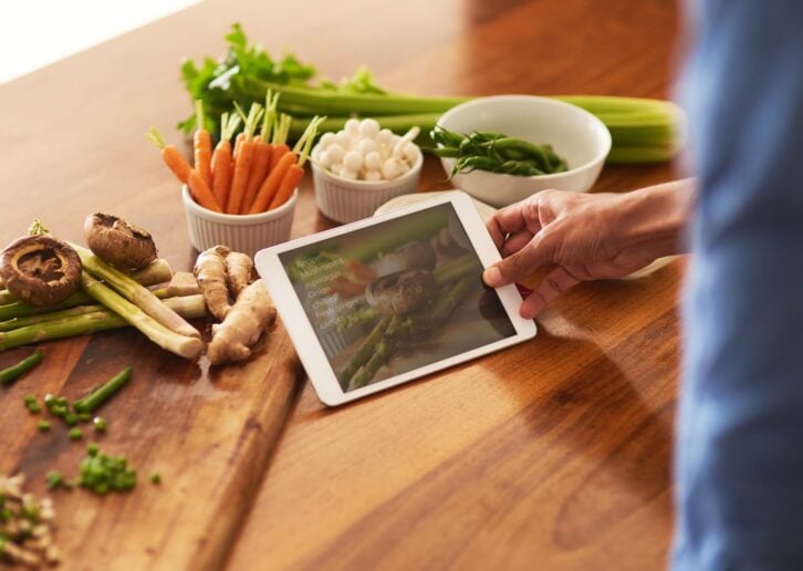 Cropped shot of a man using a digital tablet while preparing a healthy meal at home