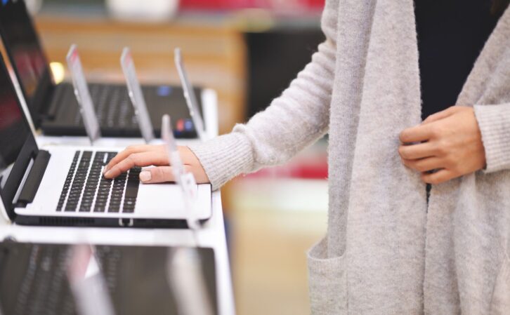 Woman chooses the laptop in electronics store, shoot with Nikon lens105 mm f/1.4