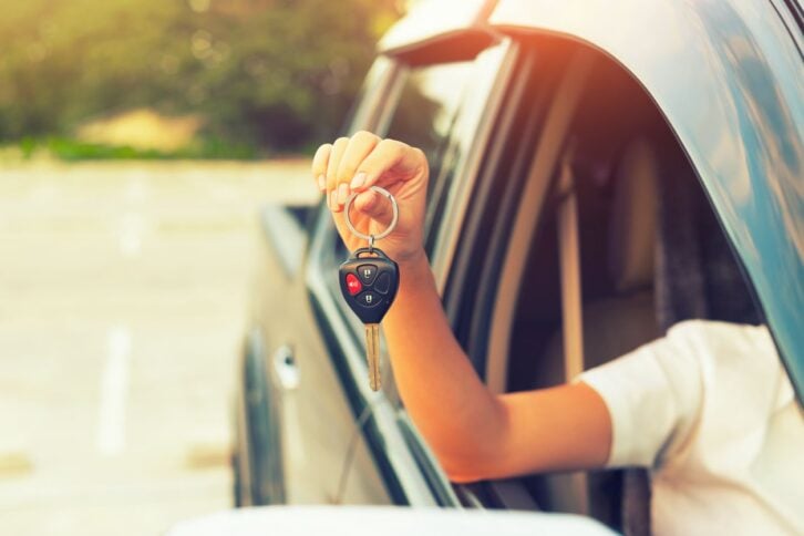 Woman's hand holding car key outside truck while sitting in it.