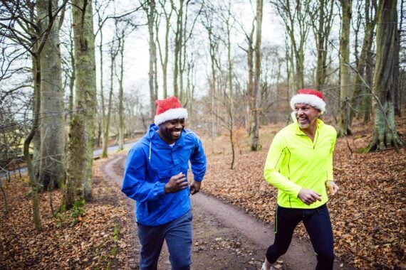 two men running with christmas hat in winter scene