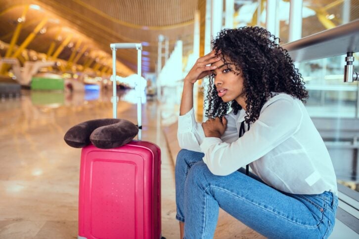 frustrated traveler sitting on floor at airport