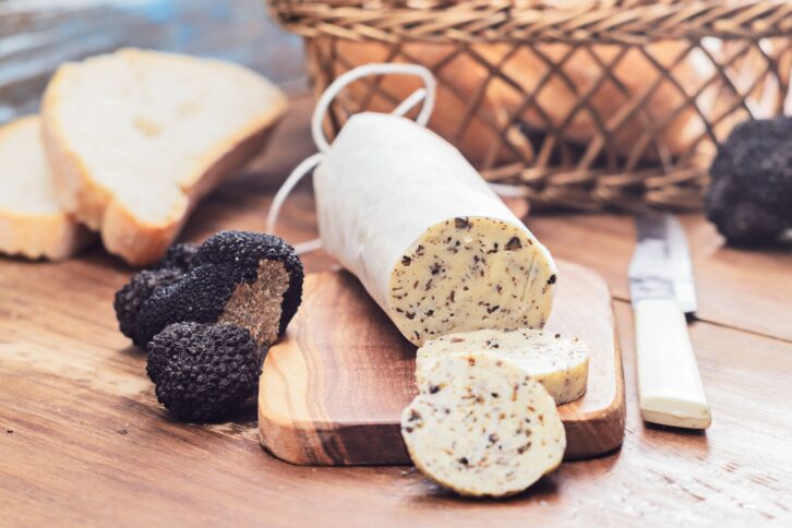 Homemade aromatic butter with black truffles on wooden board.Selective focus.