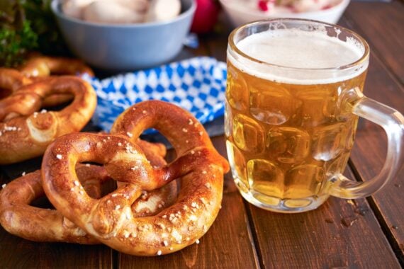 Traditional munich pretzel next to mug of beer on wooden tabele for Beer Fest. Close up.