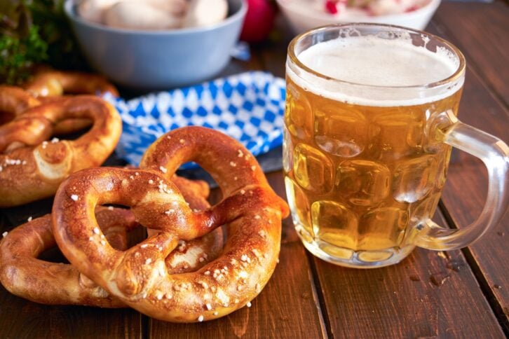 Traditional munich pretzel next to mug of beer on wooden tabele for Beer Fest. Close up.
