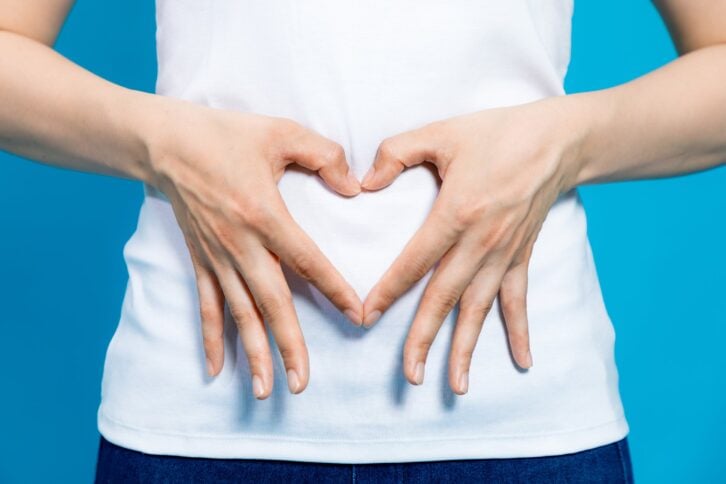 woman who makes a heart shape by hands on her stomach