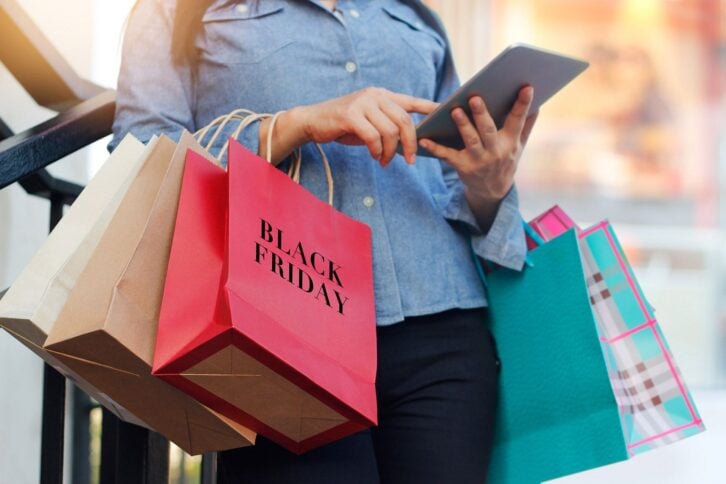 woman with tablet and black friday shopping bags