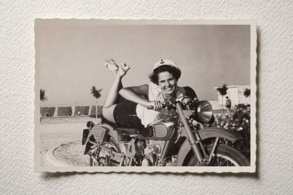 Old photograph of a smiling girl on motorbike