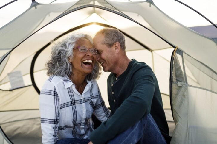senior couple whispering to each other and smiling in camping tent