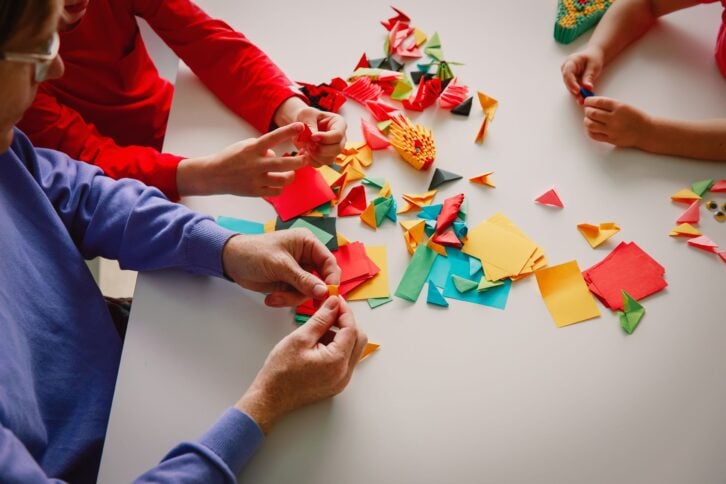 teacher and kids making origami crafts with paper
