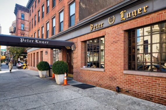 Peter Luger steak house in Williamsburg Brooklyn facade view with front door, awning and sidewalk.
