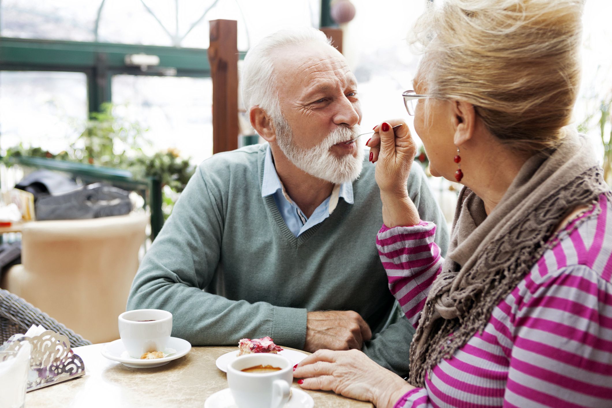 senior couple spoon-feeding each other cake