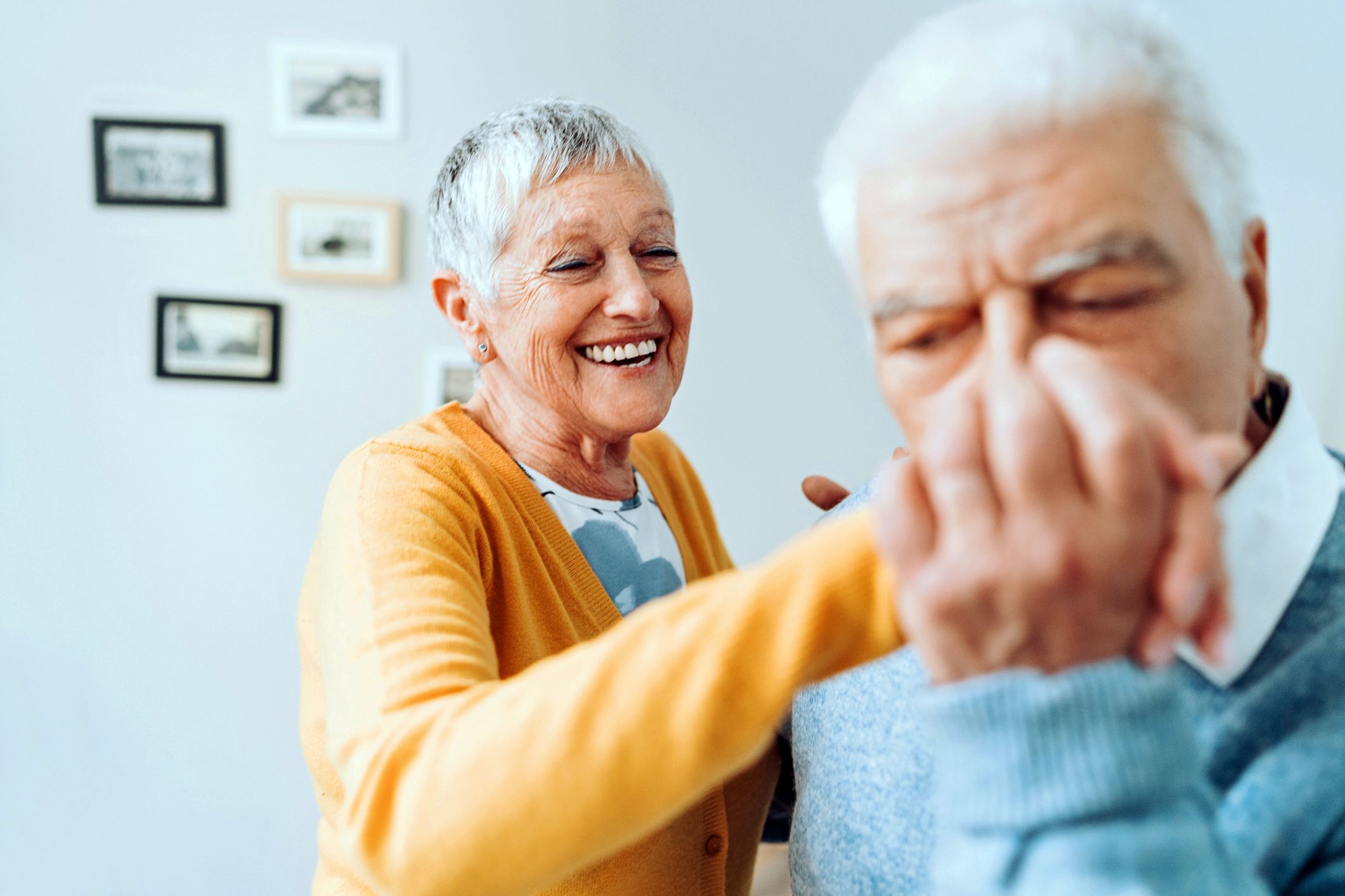 senior woman smiling as senior man kisses her hand