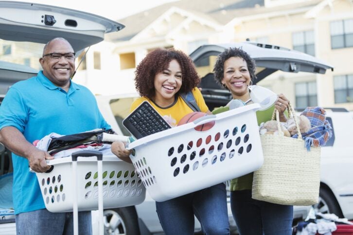 Mature African-American parents helping their daughter relocate, perhaps into an apartment or college dorm.  They are in a parking lot unloading their cars.
