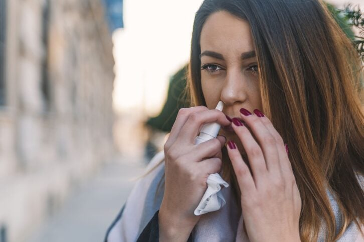 woman using nasal spray outside