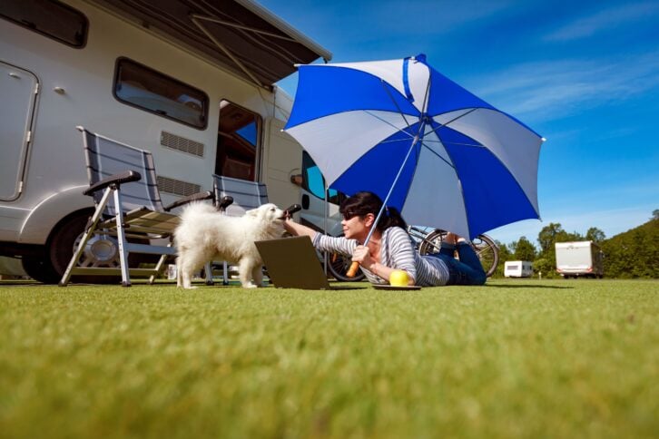 woman and dog in grass outside rv