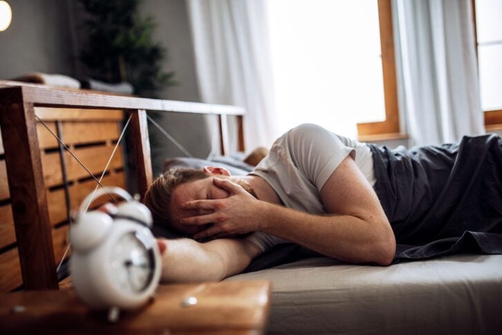man with headache sleeping in bed