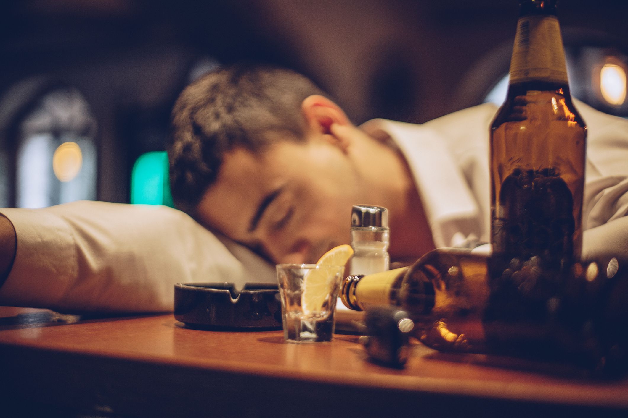 Young drunk man sleeping on bar counter in pub