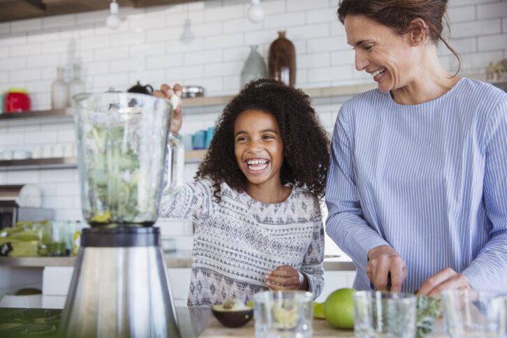 mother and daughter making green smoothie