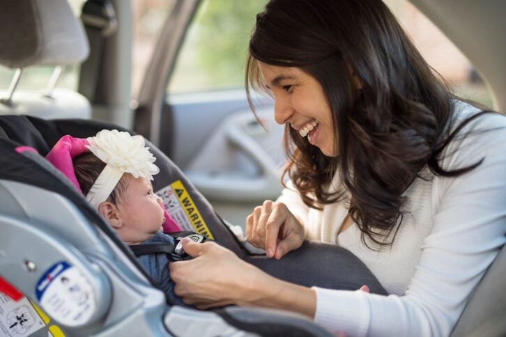 mom buckling infant into car seat