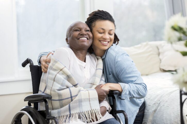 young woman smiling hugging smiling senior woman at home