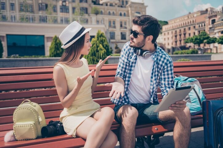Young married couple got lost on vacation in town. Frustrated lady is arguing with her boyfriend, who holds pda, has no idea where they are