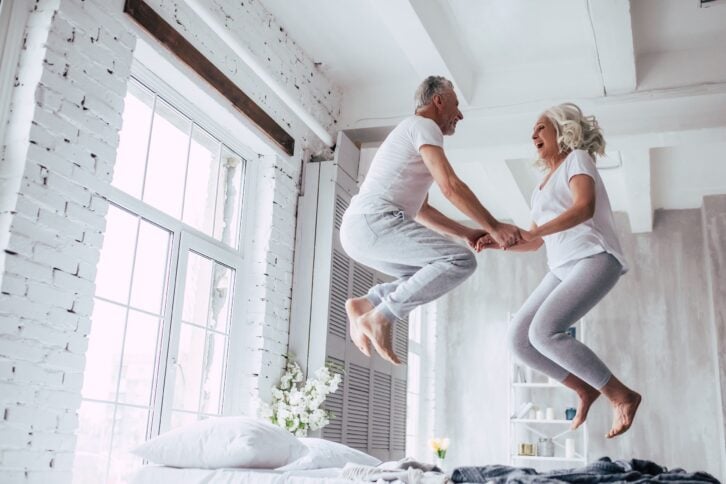senior couple jumping on bed at home