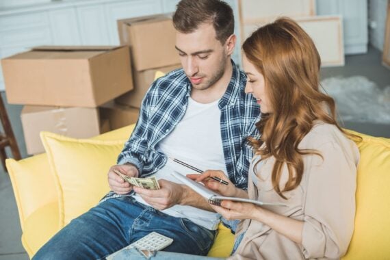 young couple taking notes and counting money while moving home